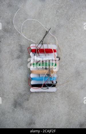 Multicoloured sample cotton threads with sewing needles Stock Photo