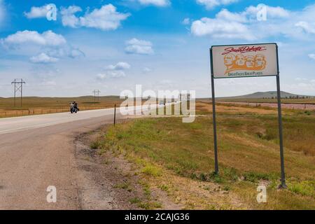 South Dakota, USA - August 8, 2014: A South Dakota State welcome sign along the US Highway 212 in the USA, with a biker riding his motorcycle. Stock Photo