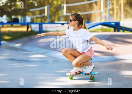 Girl teenager learns to keep balance on a skateboard in the park Stock Photo