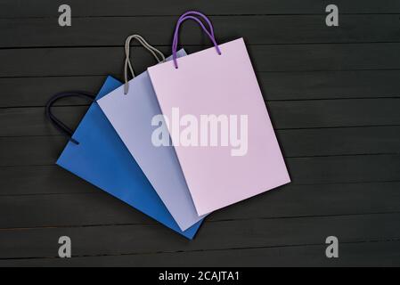Paper multi-colored shopping bags on black wooden background. Top view. Stock Photo