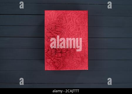 Red closed shiny cardboard box on a black wooden background. Top view. Present Stock Photo