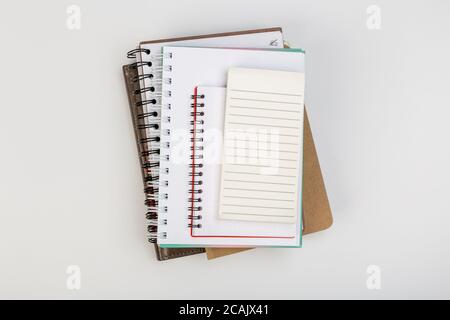 a stack of several spiral school notebooks lies on a white table with a pencil, office concept Stock Photo