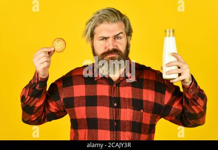 bearded man drink useful milk with pastry. Gingerbread cookie in a hot cup of milk. American famous snack. Cookies and cream in fresh milk glass. happy farmer eat cookie dessert. Stock Photo