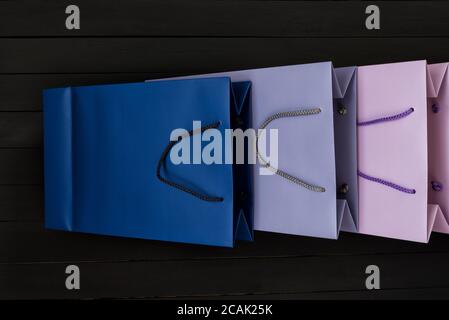 Paper multi-colored shopping bags on black wooden background. Top view. Stock Photo