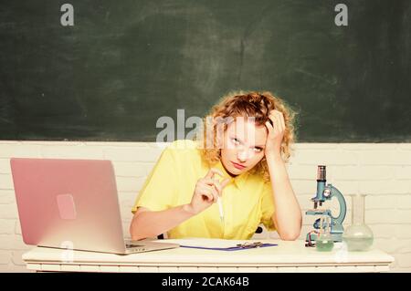 make notes about chemistry research results. girl in classroom laboratory with computer. upset student with microscope beaker. biology experiment. scientist teacher at school lab. hard working day. Stock Photo