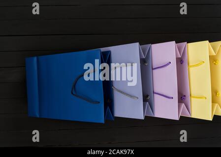 Paper multi-colored shopping bags on black wooden background. Top view. Stock Photo