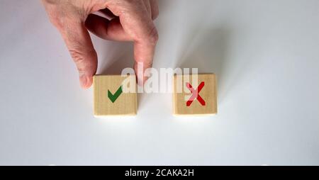 Hand making a choice between two cubes with Yes and No on white background. Stock Photo