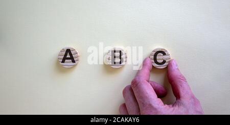 Wooden circles with letters a, b, c and hand holding one of circles. Conceptual image of business planning and different options. Stock Photo