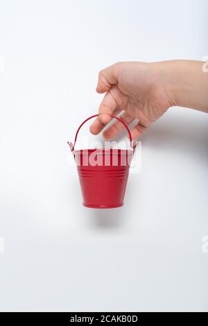 Small red bucket in children's hand on white background. Stock Photo