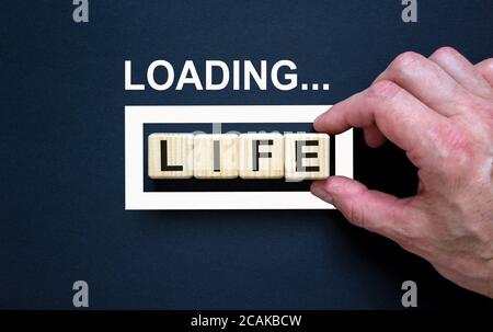 Loading word 'life' with hand putting wood cube in progress bar. Business concept. Stock Photo