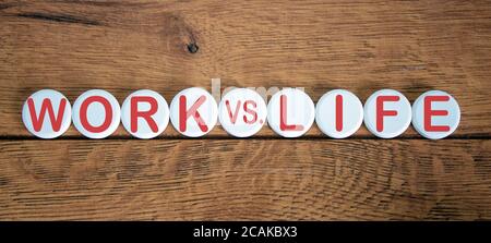 The words 'work vs life' on white circles on wooden table. Beautiful background, copy space. Stock Photo