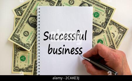 Male hand writing 'successful business' on white note, on white background. Dollar bills. Stock Photo