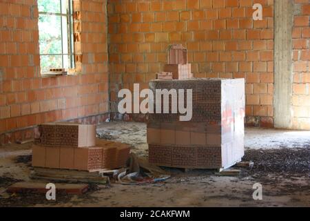 a stack of red bricks to build a residential house within the structure Stock Photo