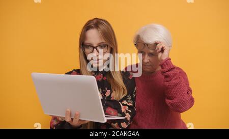 Young woman explaining to a senior lady how to use laptop. High quality photo Stock Photo