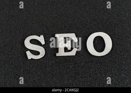 Word SEO from white wooden letters on black background. search engine optimization . Stock Photo