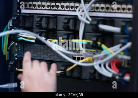 An Expert Engeneer in datacenter server room  connecting cables in server cabinet in network server room. Stock Photo