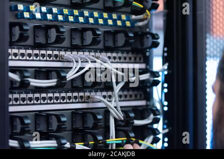 An Expert Engeneer in datacenter server room  connecting cables in server cabinet in network server room. Stock Photo