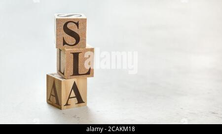 Three wooden cubes with letters SLA (stands for Service Level Agreement) on  white board Stock Photo - Alamy