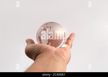 Hand man holding glass earth on isolated background. Concept of caring for the environment and the fragile weakness of the world Stock Photo