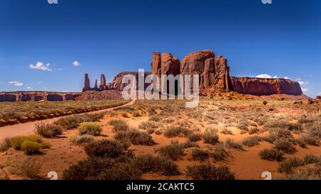 The Three Sisters and Mitchell Mesa, a few of the many massive Red Sandstone Buttes and Mesas in Monument Valley, Utah, United States