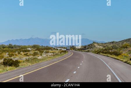 Big truck rig powerful popular industrial classic semi truck running on the winding mountain road on USA Stock Photo