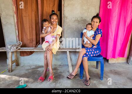 Haikesa / Indonesia - August 10, 2018: Two young Timorese women hold babies in Indonesian village Stock Photo