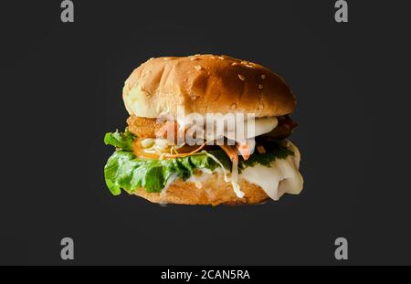 Fresh testy burger with tomatoes, Cheese ,Green lettuce, onion and salad isolated on black background . Stock Photo
