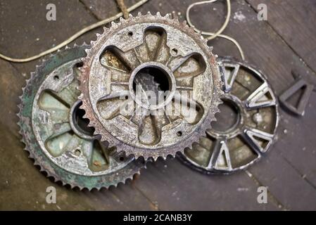 Old motorcycle drive stars on the desktop in the garage, motorcycle spare parts. Stock Photo