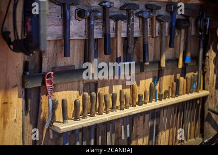 Old tools - hammers and files of different sizes on a wooden wall. Stock Photo