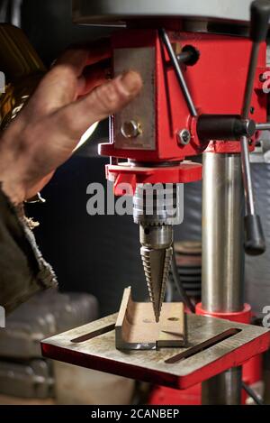 Hands of a man who drills a metal part on a machine tool in a home workshop. Stock Photo