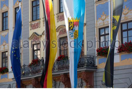 Four flags hanging in sunshine on the town hall of Coburg in Bavaria, the EU flag, the German flag as well as the Bavarian and Coburg flags. Stock Photo