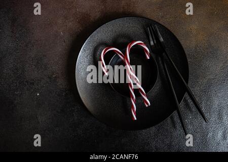 Minimalistic table setting with black ceramic plate and festive decor on concrete background Stock Photo