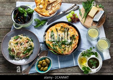 Appetizing classic Italian cuisine on rustic wooden table. Different types of pizza, pasta, snacks and capreze. Healthy homemade food. Stock Photo
