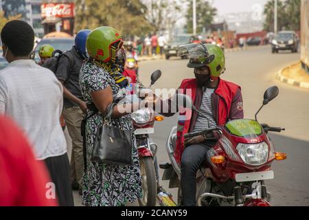 (200808) -- KIGALI, Aug. 8, 2020 (Xinhua) -- A motorist provides sanitizer to a customer in Kigali, capital city of Rwanda, on Aug. 6, 2020.  Rwanda's commercial motorists, commonly known as motorcycle taxis, will begin to adopt cashless payment services to promote cashless economy, the Rwanda Utilities Regulatory Authority (RURA) said Wednesday. (Photo by Cyril Ndegeya/Xinhua) Stock Photo