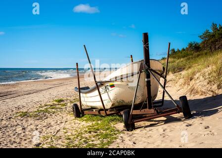 A baywatch boat parked on the beach near the dunes on a hot summer day with sea behind it and clear blue sky Stock Photo