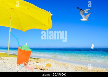 beach umbrella and cocktail under flying seagulls Stock Photo