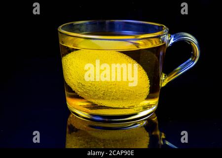 the process of dyeing eggs for Easter. egg in a transparent mug with dye.  Stock Photo
