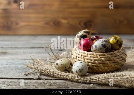 Hand painted easter eggs in wicker basket on burlap napkin on wooden background Stock Photo
