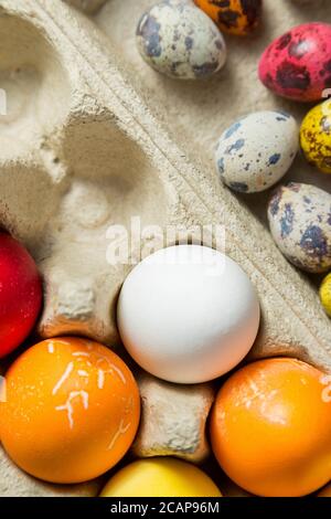 Dyed easter eggs in cardboard box on wooden background. Stock Photo