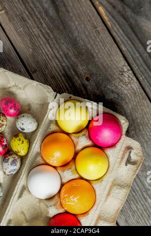 Dyed easter eggs in cardboard box on wooden background. Stock Photo