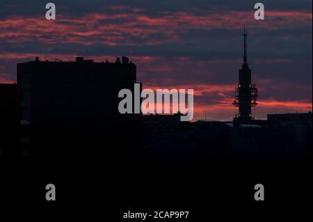 Helsinki / Finland - August 6, 2020: A silhouette of a tall telecommunication / broadcasting tower against vivid red sky on a cloudy summer evening. Stock Photo