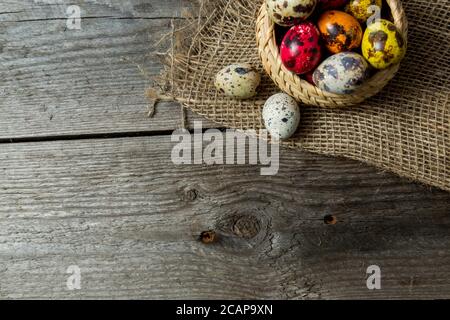 Hand painted easter eggs in wicker basket on burlap napkin on wooden background Stock Photo