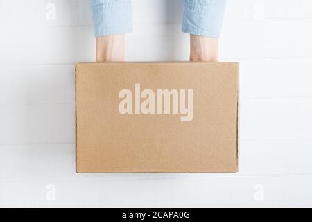 Rectangular cardboard box in female hands. Top view, white background Stock Photo