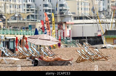 Brighton UK 8th August 2020 - Sunbathers on Brighton beach as the temperature is forecast to reach over 30 degrees in some parts of the South East : Credit Simon Dack / Alamy Live News Stock Photo