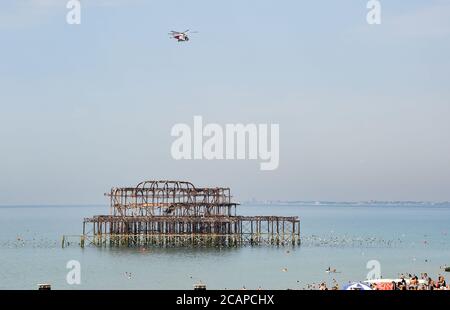 Brighton UK 8th August 2020 - The coastguard helicopter above Brighton's West Pier as the temperature is forecast to reach over 30 degrees in some parts of the South East : Credit Simon Dack / Alamy Live News Stock Photo