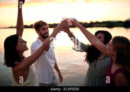 group of friends having toast at sunset by the river Stock Photo