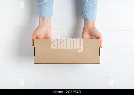 Rectangular cardboard box in female hands. Top view, white background Stock Photo