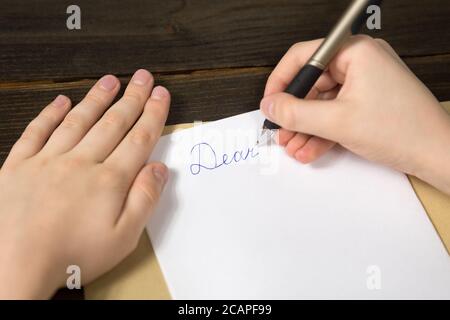 Children's hands writing a letter to Santa. Wooden background. Close-up Stock Photo