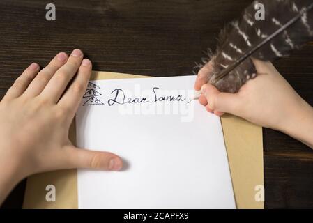 Children's hands writing a letter to Santa. Wooden background. Close-up Stock Photo