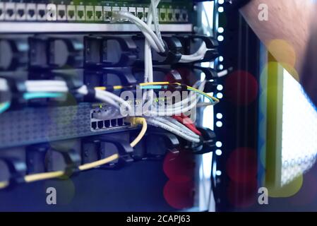 An Expert Engeneer in datacenter server room  connecting cables in server cabinet in network server room. Stock Photo